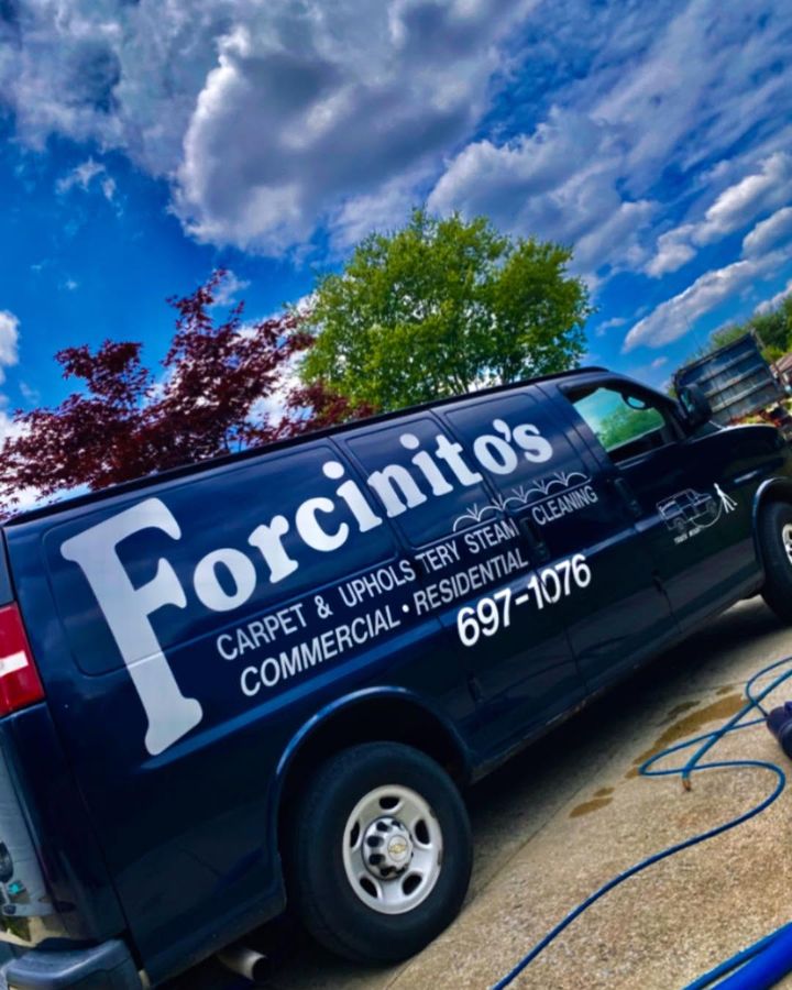 The navy Forcinito’s van parked at a customer’s home with cleaning hoses running inside